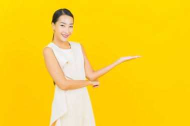 Asyalı güzel bir kadının portresi. Sarı arka planda hareketli gülümsüyor.