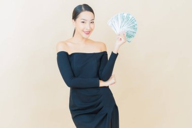 Asyalı güzel bir kadının portresi. Renkli arka planda bol para ve parayla gülümsüyor.