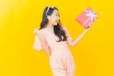 Güzel bir Asyalı kadının portresi. Arka planda kırmızı hediye kutusuyla gülümsüyor.