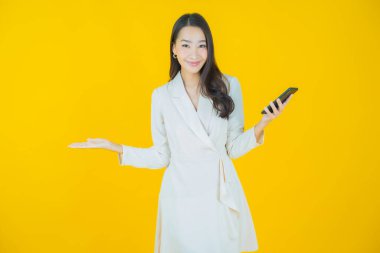 Renkli arka planda akıllı cep telefonuyla güzel Asyalı kadın gülümsemesi