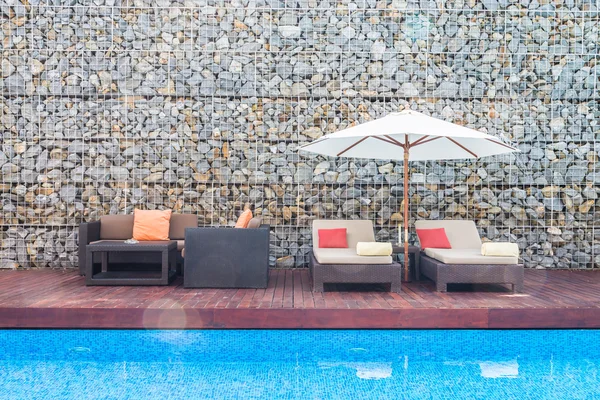Cadeiras com deck guarda-chuva e resort de piscina — Fotografia de Stock