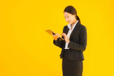 Güzel, genç Asyalı bir kadının portresi mutlu bir gülümseme ve sarı izole edilmiş arka planda akıllı tabletler.