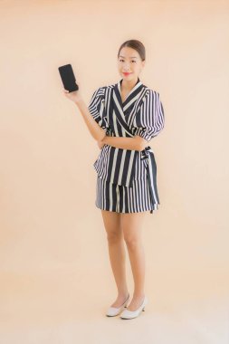 Kahverengi arka planda akıllı cep telefonlu güzel Asyalı kadın portresi.