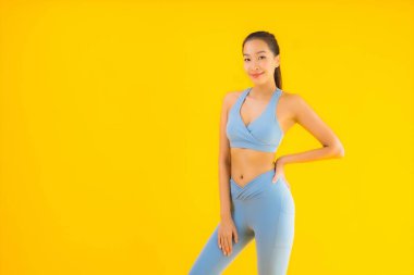 Sarı izole edilmiş arka planda spor giysili güzel Asyalı kadın portresi egzersize hazır.