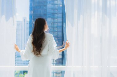 Güzel bir Asyalı kadın portresi. Perde camını aç ve pencereden dışarı bak.