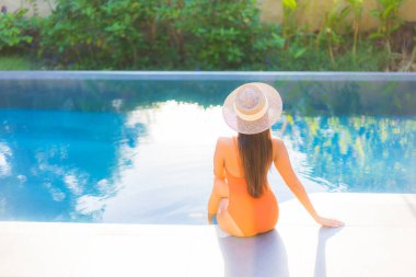 Güzel bir Asyalı kadının portresi tatil için yüzme havuzunda rahatlıyor.