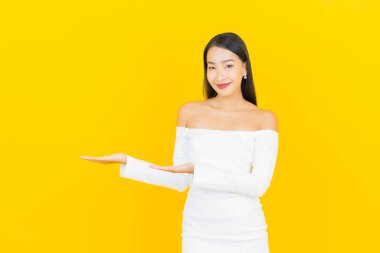 Portre güzel genç iş kadını gülümseyen ve eylem sarı arka planlı Asyalı kadın