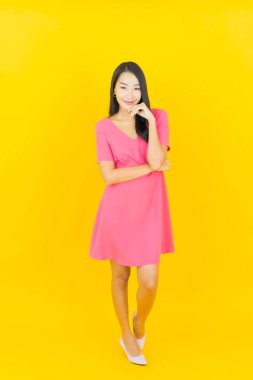 Asyalı güzel bir kadının portresi. Sarı arka planda hareketli gülümsüyor.