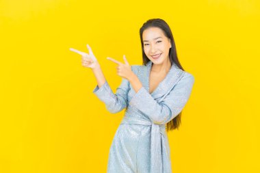 Asyalı güzel bir kadının portresi. Sarı arka planda hareketli gülümsüyor.