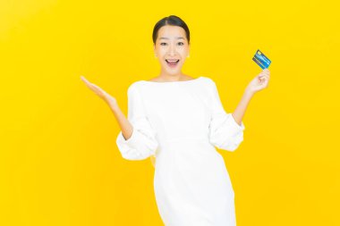 Renkli arka planda akıllı cep telefonuyla güzel Asyalı kadın gülümsemesi