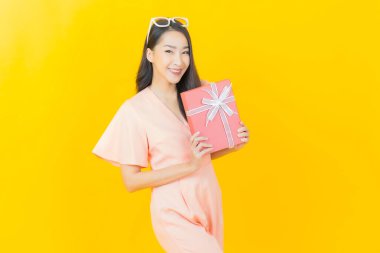 Güzel bir Asyalı kadının portresi. Arka planda kırmızı hediye kutusuyla gülümsüyor.