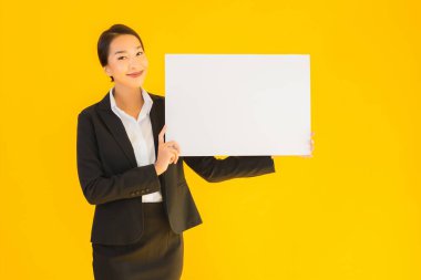 Güzel bir portre. Genç Asyalı kadın, sarı izole edilmiş arka planda boş beyaz tahta gösteriyor.