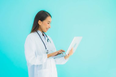 Bilgisayarlı güzel Asyalı doktor kadın portresi klinikte ya da mavi izole arka planda hastanede kullanılacak.