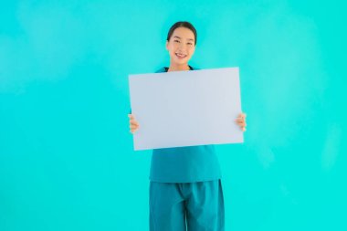 Fotokopi için boş kâğıt tahtası olan güzel Asyalı genç doktor kadın hastane ve klinikteki sağlık hizmetleri konseptinde mavi izole edilmiş arka plan.