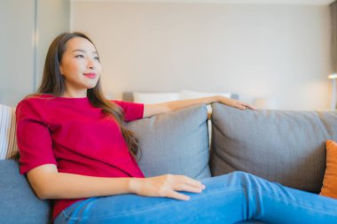 Güzel bir Asyalı kadın portresi. Yatak odasındaki kanepede rahatla. Gülümse.