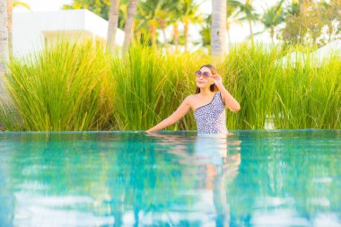 Güzel bir Asyalı kadın portresi. Rahatlayın, gülümseyin. Tatil için oteldeki yüzme havuzunun keyfini çıkarın.