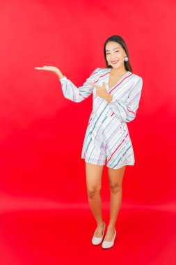 Güzel bir Asyalı kadının portresi kırmızı arka planda birçok hareketle gülümsüyor.