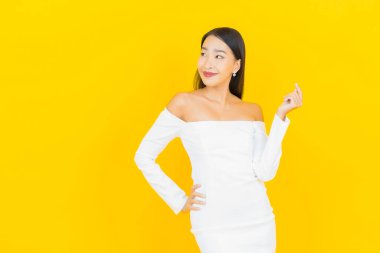 Portre güzel genç iş kadını gülümseyen ve eylem sarı arka planlı Asyalı kadın