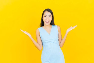 Asyalı güzel bir kadının portresi. Sarı arka planda hareketli gülümsüyor.