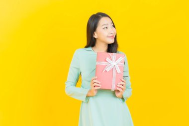 Güzel bir Asyalı kadının portresi. Arka planda kırmızı hediye kutusuyla gülümsüyor.