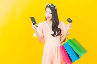 Portre güzel Asyalı kadın tebessümü ile renk arka planında alışveriş torbası