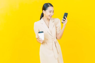 Renkli arka planda akıllı cep telefonuyla güzel Asyalı kadın gülümsemesi