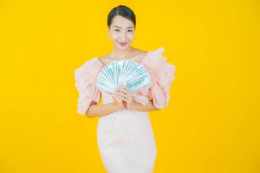 Asyalı güzel bir kadının portresi. Renkli arka planda bol para ve parayla gülümsüyor.