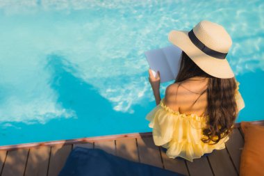 Genç Asyalı kadının portresi oteldeki havuzda kitap okuyordu.