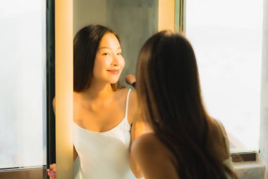 Güzel bir Asyalı kadın portresi makyaj malzemesi makyaj malzemesi ve yüz makyajı ile banyo içinde yüz maskesi.