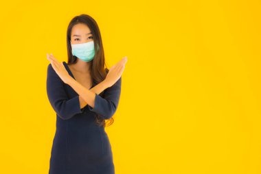 Koronavirüsten korunmak için maske takmış güzel Asyalı bir kadın portresi ve sarı izole edilmiş arka planda 19 numara.