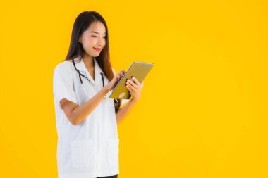 Güzel Asyalı genç doktor kadın sarı izole arka planda akıllı tablet kullanıyor.