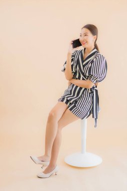 Kahverengi arka planda akıllı cep telefonlu güzel Asyalı kadın portresi.