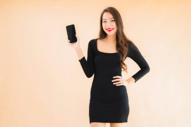 Güzel Asyalı genç bir kadının portresi mutlu bir şekilde gülümsüyor renkli arka planda akıllı cep telefonu kullan