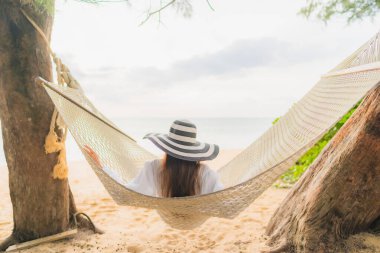 Güzel bir Asyalı kadın portresi deniz kıyısındaki hamakta dinleniyor.