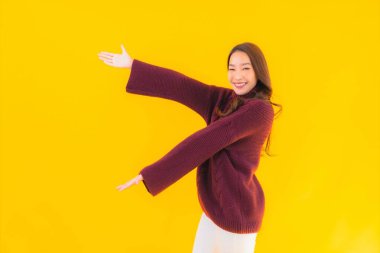 Güzel Asyalı kadın gülümsüyor. Sarı izole edilmiş arka planda başka bir eylemde mutlu.