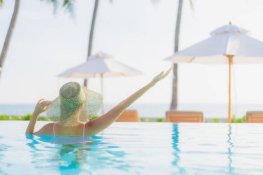 Güzel bir Asyalı kadın portresi. Tatil gezisinde deniz manzaralı açık havuz etrafında rahatça yüzebiliyor.