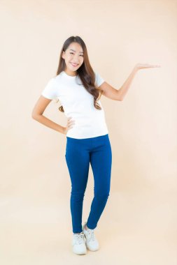 Portre güzel Asyalı kadın gülümsüyor krem rengi arka planda bir sürü aksiyon ile