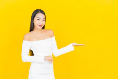 Portre güzel genç iş kadını gülümseyen ve eylem sarı arka planlı Asyalı kadın