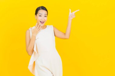 Asyalı güzel bir kadının portresi. Sarı arka planda hareketli gülümsüyor.