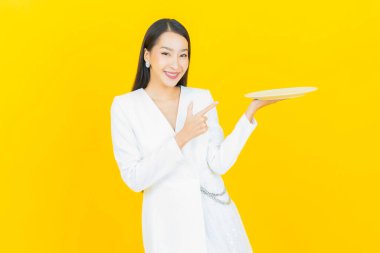 Güzel Asyalı bir kadının portresi. Arka planda boş tabak tabağıyla gülümsüyor.