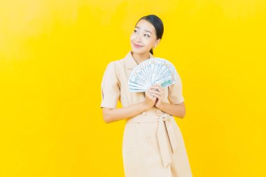 Asyalı güzel bir kadının portresi. Renkli arka planda bol para ve parayla gülümsüyor.