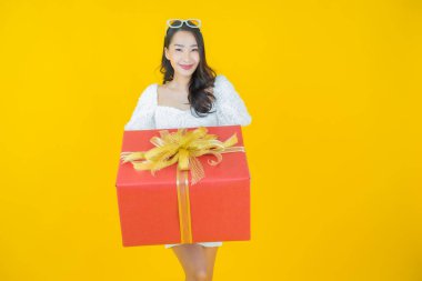 Güzel bir Asyalı kadının portresi. Arka planda kırmızı hediye kutusuyla gülümsüyor.