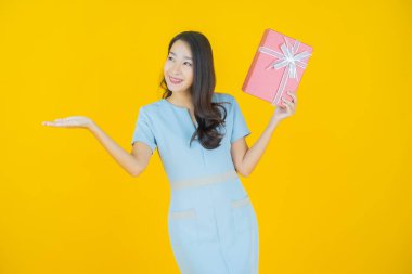 Güzel bir Asyalı kadının portresi. Arka planda kırmızı hediye kutusuyla gülümsüyor.