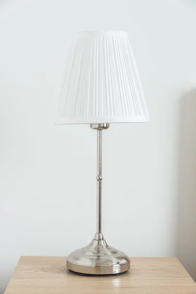 Ljus lampa bredvid sängen — Stockfoto