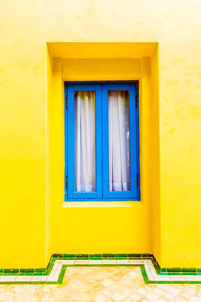 Голубое окно на желтой стене — стоковое фото