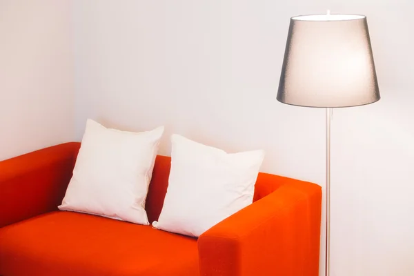 Červená pohovka s polštáři a světlo lampy — Stock fotografie
