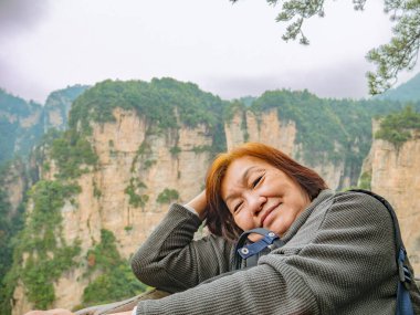 Wulingyuan İlçesi Zhangjiajie Şehri 'ndeki Zhangjiajie Ulusal Orman Parkı' nda Yuanjiajie Dağı 'nın güzel dağları olan yaşlı Asyalı kadınların portresi.