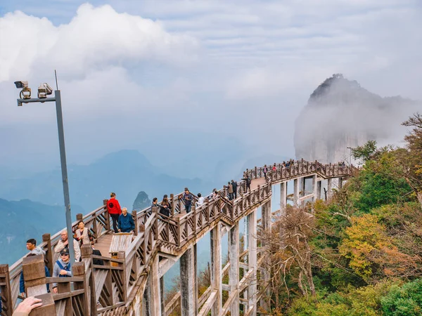 zhangjiajie / Çin - 15 Ekim 2018: Hunan şehrinin Çin kenti Zhangjiajie 'deki Tianmen Dağı ulusal parkında tahta köprüde yürüyen yabancı turistler.