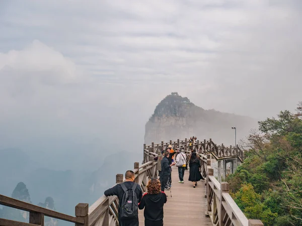 zhangjiajie / Çin - 15 Ekim 2018: Hunan şehrinin Çin kenti Zhangjiajie 'deki Tianmen Dağı ulusal parkında tahta köprüde yürüyen yabancı turistler.