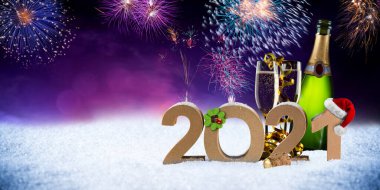 Yeni yıl arifesi 2021 Noel Baba şapkalı renkli havai fişekler dört yapraklı yonca şişesi kar üzerinde şampanya şişesi kırmızı mor Bokeh gece arkaplanı